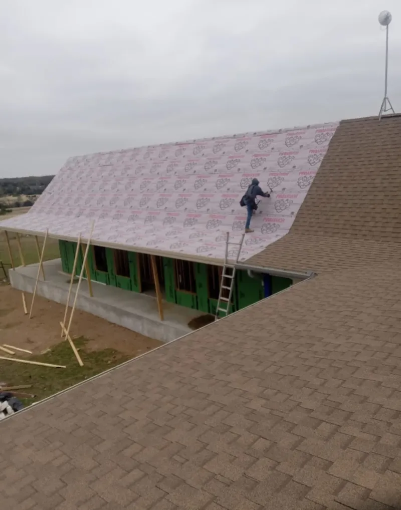 Worker preparing underlayment for a metal roof installation in Fort Carson